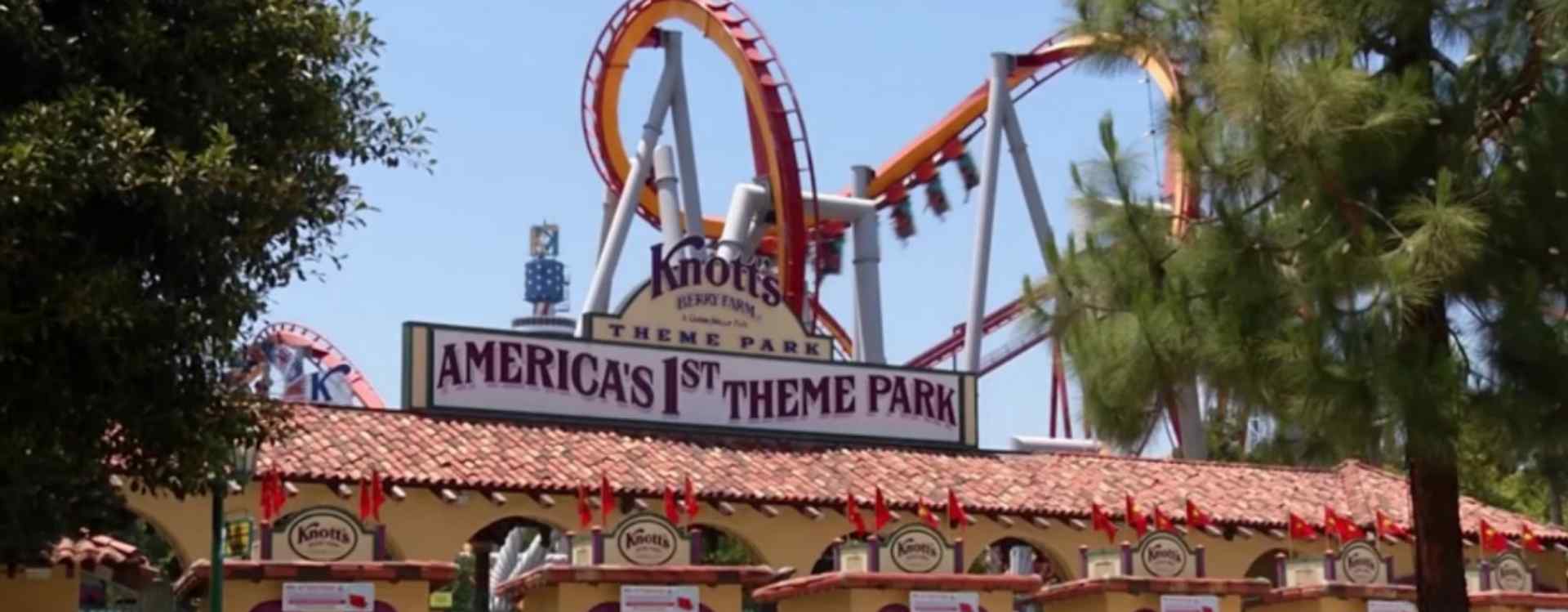 Entrance of Knott's Berry Farm, featuring "America's 1st Theme Park" sign with vibrant roller coasters in the background on a sunny day.