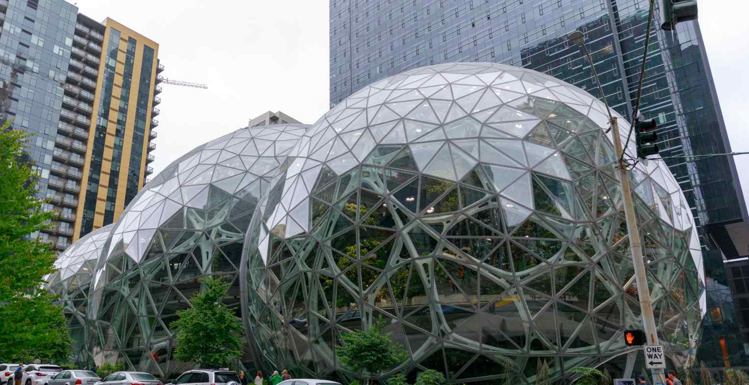 The Amazon Spheres in Seattle, featuring interconnected glass domes with greenery, juxtaposed against urban buildings.