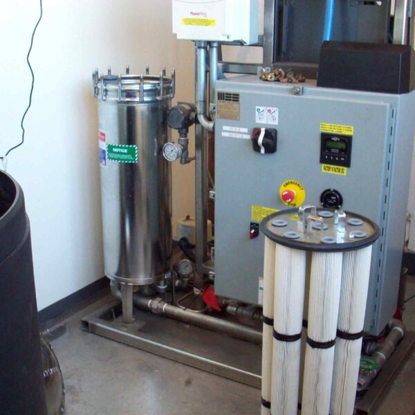 Industrial water filtration system featuring a stainless steel filter, control panel, and cylindrical filter cartridges.