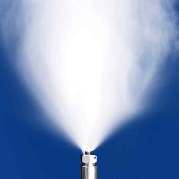Close-up of a nozzle emitting a fine mist against a bright blue background, creating a cloud-like spray.