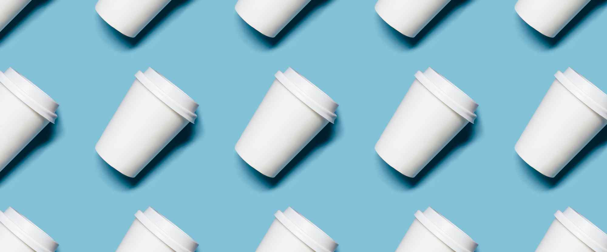Pattern of white coffee cups on a pastel blue background, showcasing a modern and clean design aesthetic.