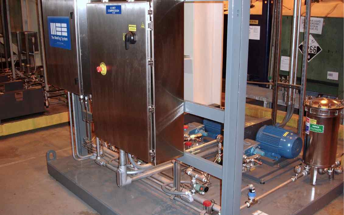 Industrial equipment setup featuring stainless steel cabinets, pumps, and piping for a wet compression system.