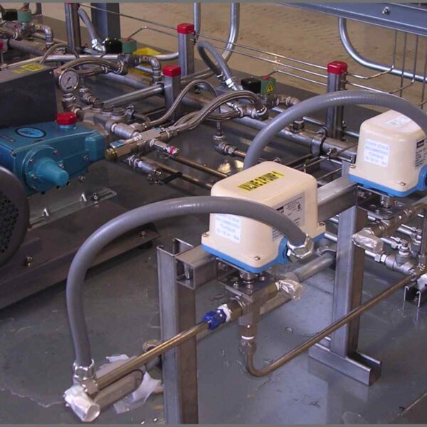 A complex arrangement of motors, pipes, and valves on a metal platform, used for fluid control in industrial applications.