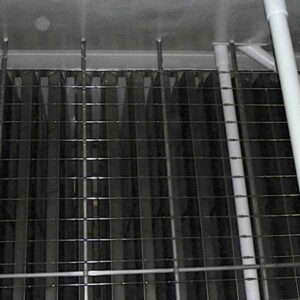 Close-up of a grid-like metal structure with vertical bars and a white pipe, set against a dark background.