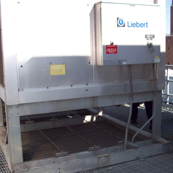A large silver air conditioning unit labeled "Liebert" on a rooftop, with metal grating flooring and a person in the background.
