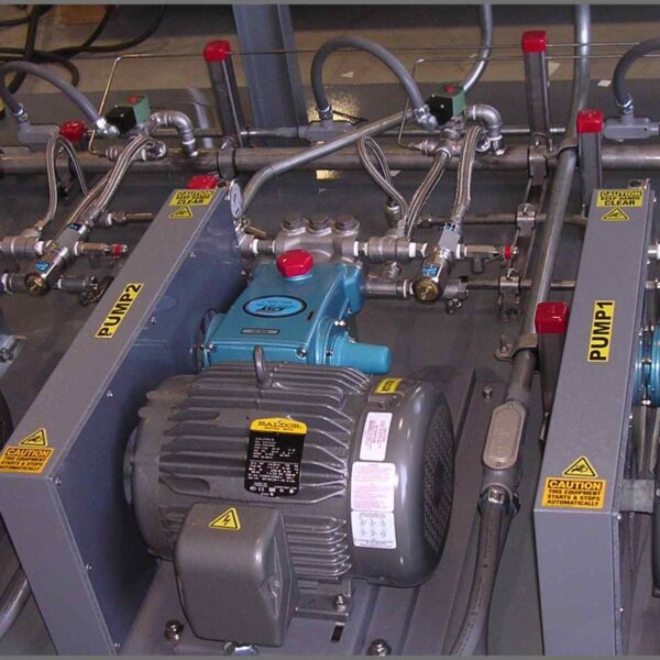 Close-up of two industrial pumps with electric motors, valves, and piping on a workstation, labeled "PUMP1" and "PUMP2."