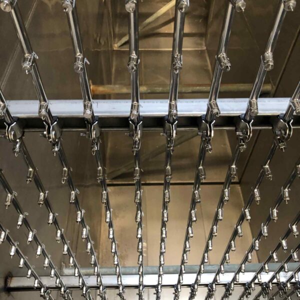Close-up of a metallic framework with parallel rods and clips, reflecting industrial design in a shiny, stainless steel environment.