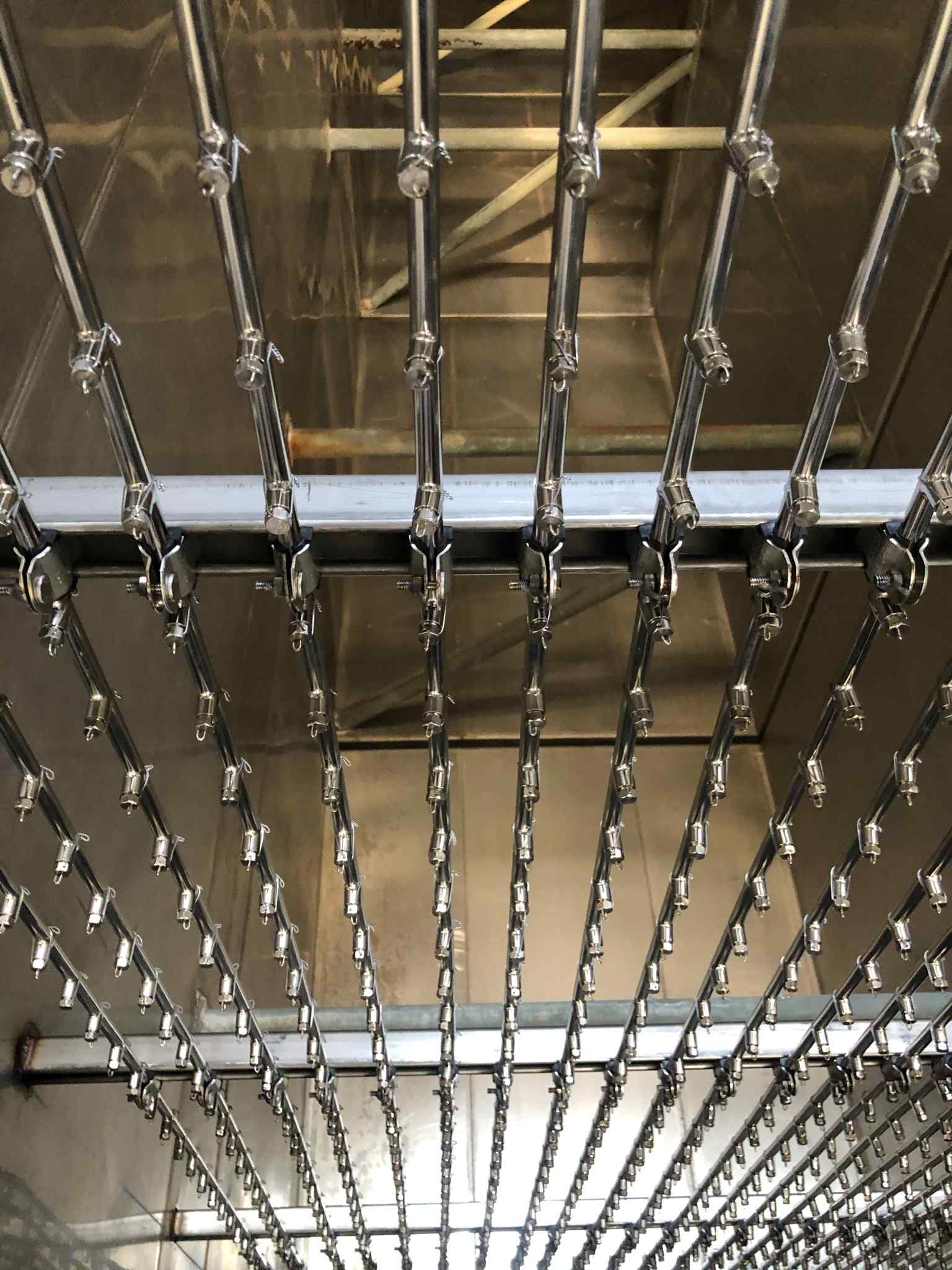 Close-up of a metallic framework with parallel rods and clips, reflecting industrial design in a shiny, stainless steel environment.