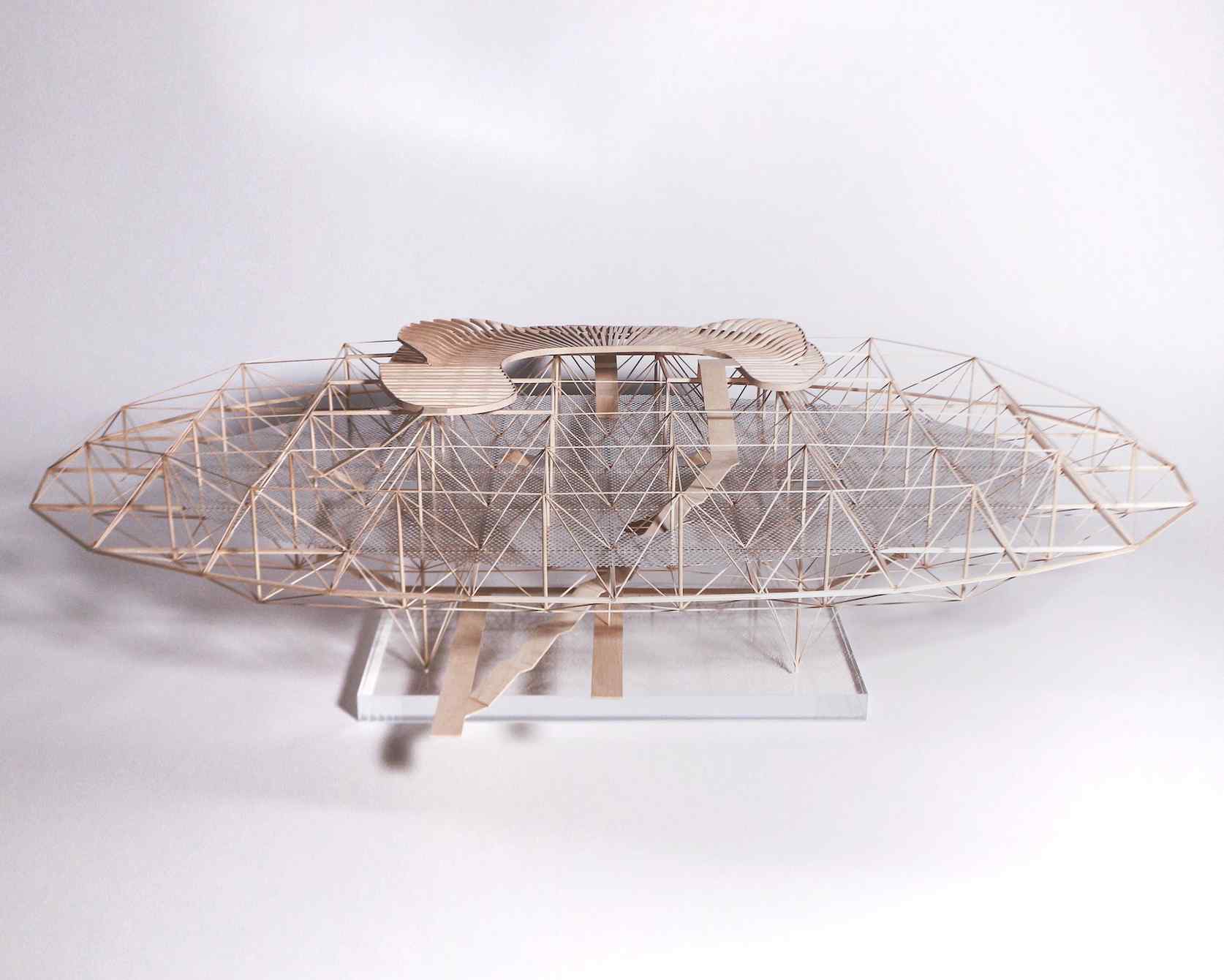 A detailed architectural model resembling a futuristic structure with a geometric wooden framework and a smooth, curved top.