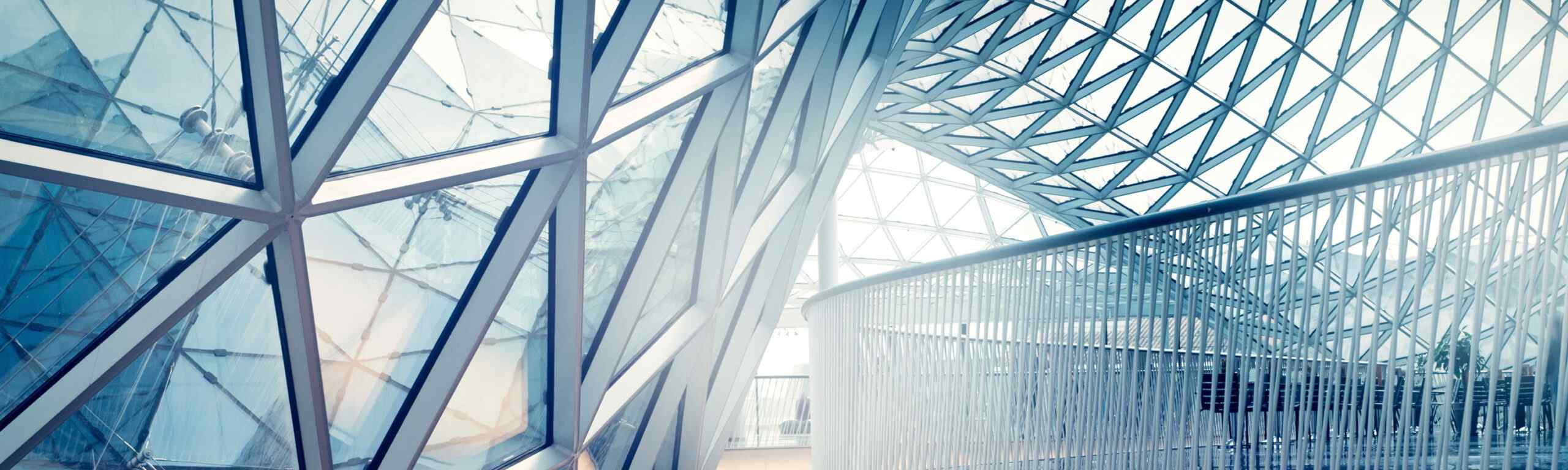 A modern architectural space featuring a striking glass and steel structure with intricate geometric patterns and natural light.