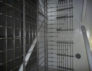 Interior view of a mechanical system featuring a network of stainless steel pipes and connectors arranged on a white wall.