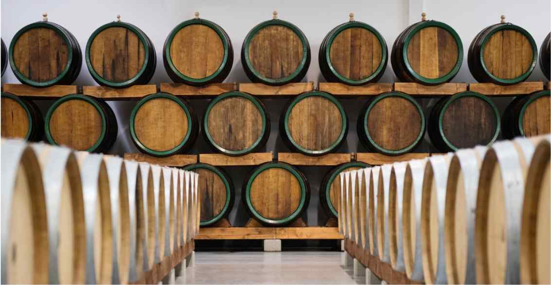 A wine cellar featuring rows of wooden barrels stacked on shelves, creating a rustic, atmospheric setting for aging wine.
