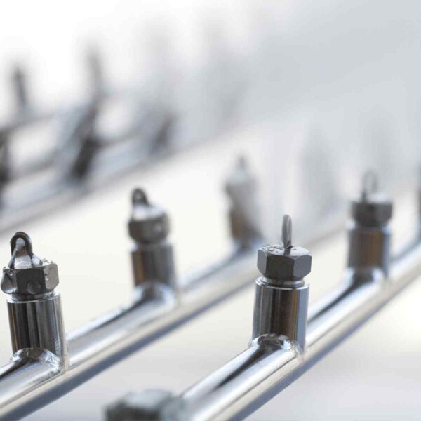 Close-up of metallic piping with threaded nuts and hooks, arranged in a linear perspective against a softly blurred background.