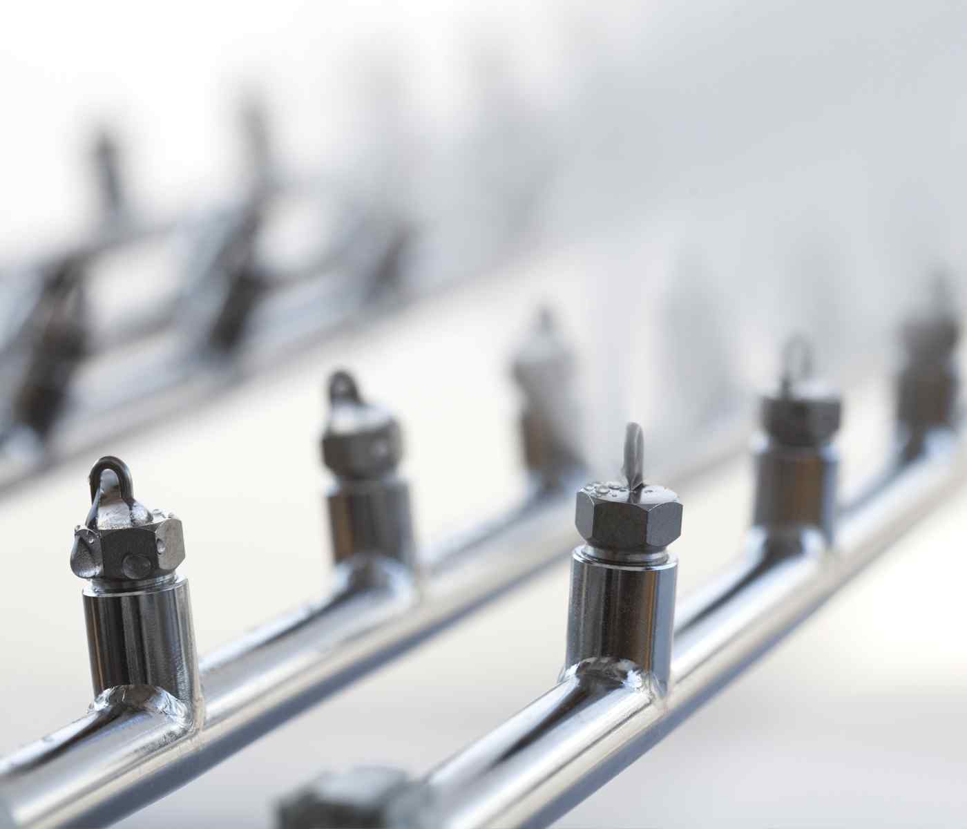 Close-up of metallic piping with threaded nuts and hooks, arranged in a linear perspective against a softly blurred background.