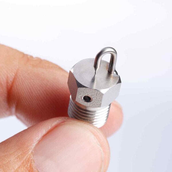 Close-up of a person's finger holding a metallic nozzle, showcasing its threaded base and a bent tip for fluid delivery.