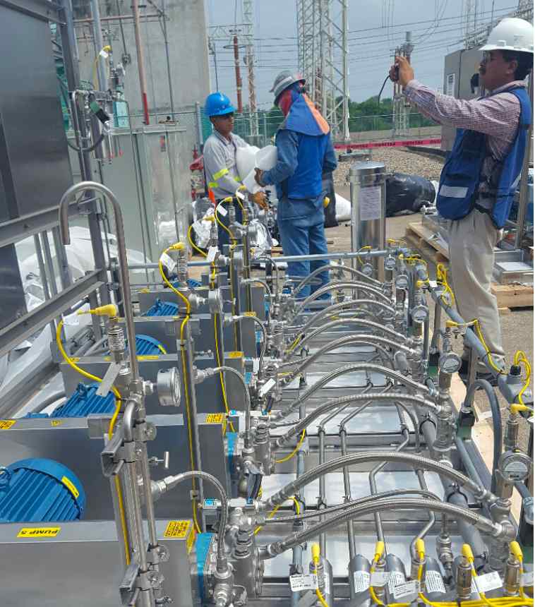 Workers are assembling industrial equipment with visible machinery, piping, and safety gear in a power facility.