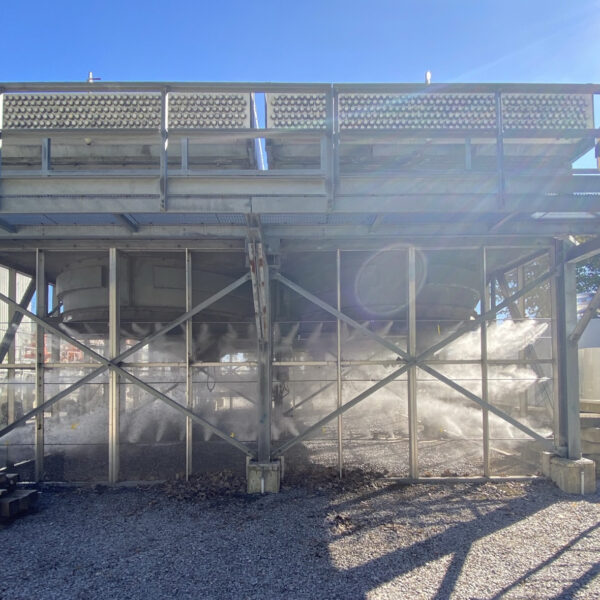 the underside of an industrial cooling tower with circular shapes of axial fan assemblies mounted at the top.