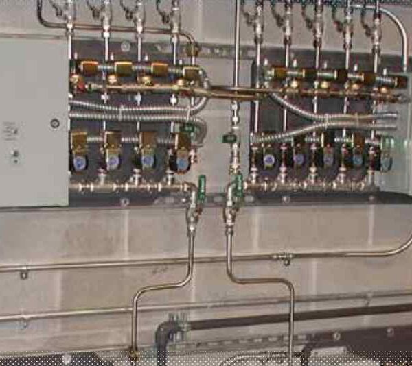 A complex arrangement of valves and control panels mounted on a concrete wall, used for managing fluid systems.