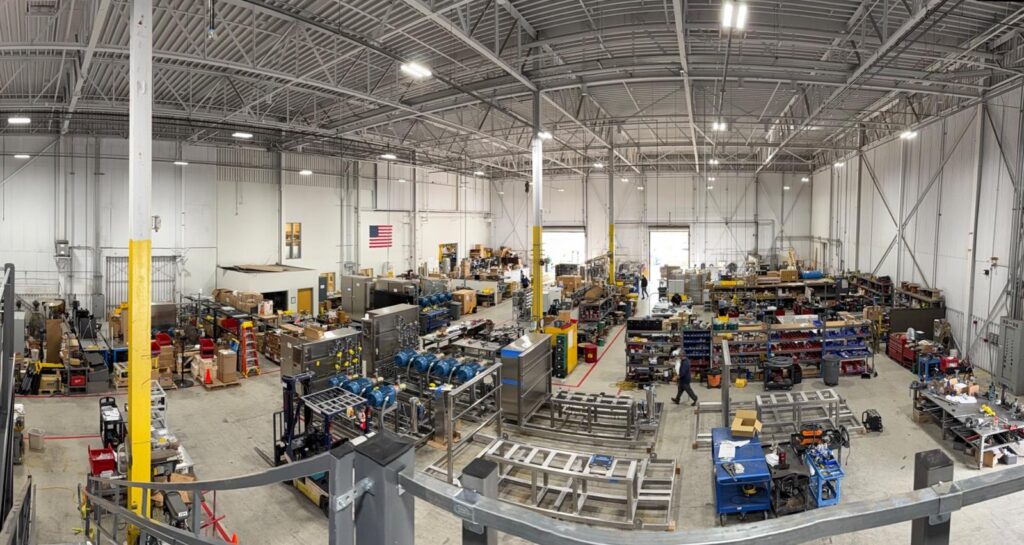 Mee Industries manufacturing facility with industrial pump systems and assembly lines inside a large warehouse.