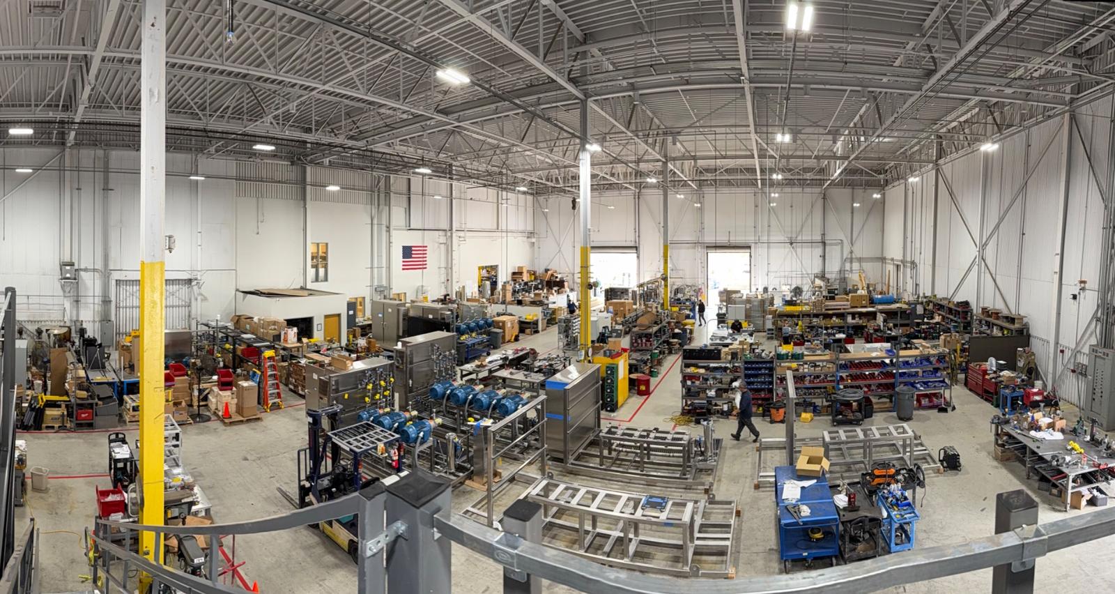 Mee Industries manufacturing facility with industrial pump systems and assembly lines inside a large warehouse.