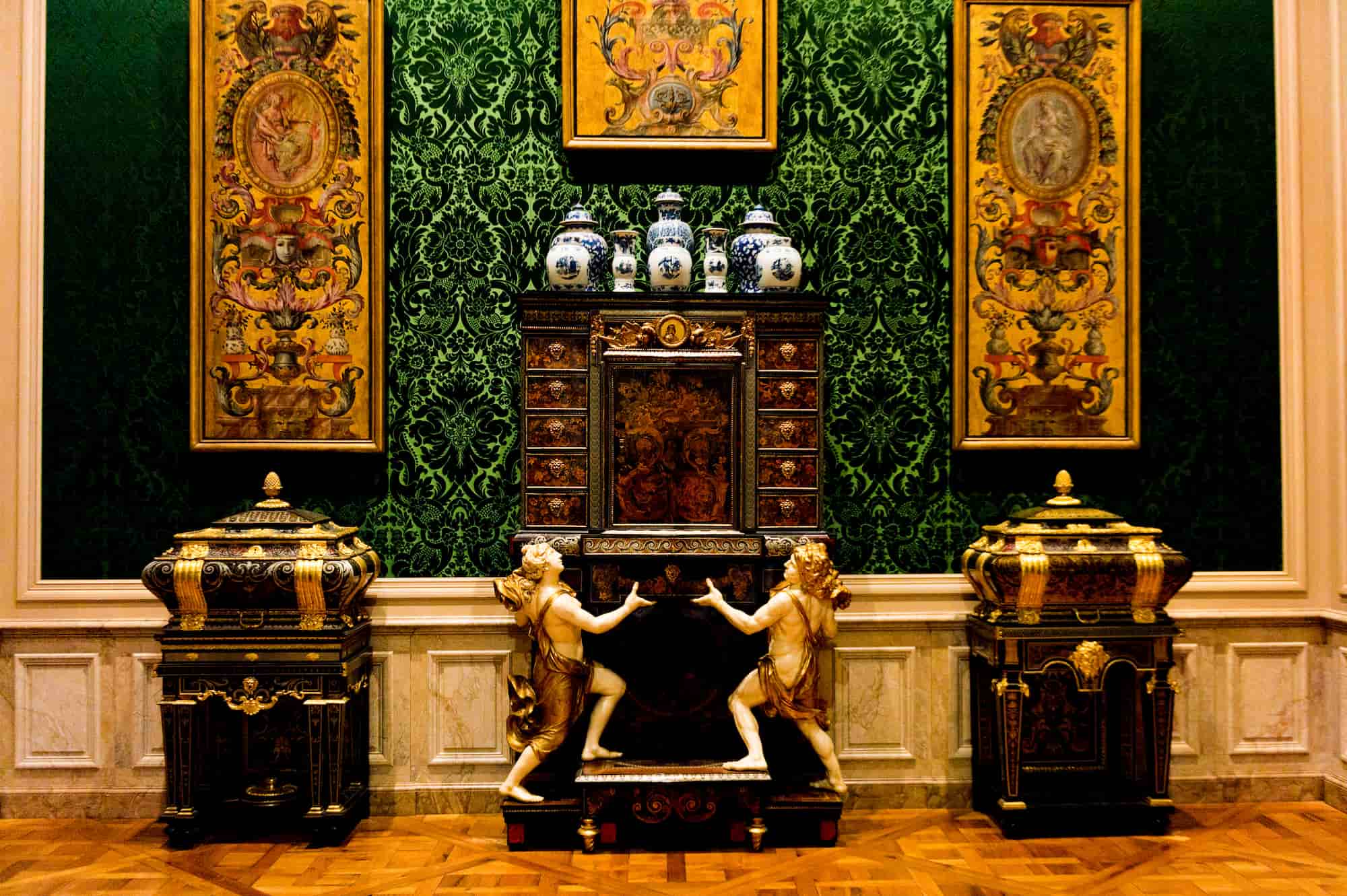 A historic interior installation featuring a 17th-century French cabinet on a stand and intricate gilt-bronze furniture.