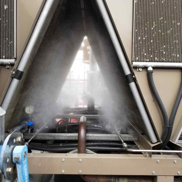 Steam rises from a cooling system, showing pipes and coils in a triangular configuration, with gauges and valves visible.