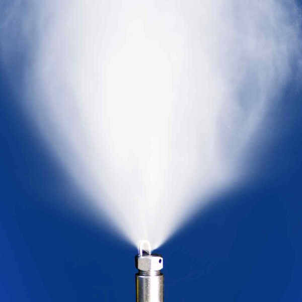 Close-up of a metallic nozzle emitting a fine mist against a blue background, creating a soft, white spray effect.