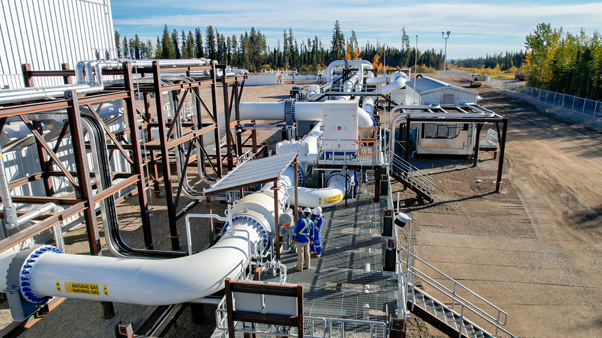 TC Energy natural gas compressor station in Lachenaie, Canada. Two workers are inspecting the large white pipeline that requires MeeFog cooling for pipeline integrity.