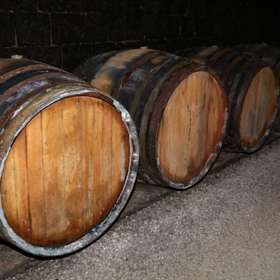 Barrels aging in a cellar with whitish, chalky-looking deposits.