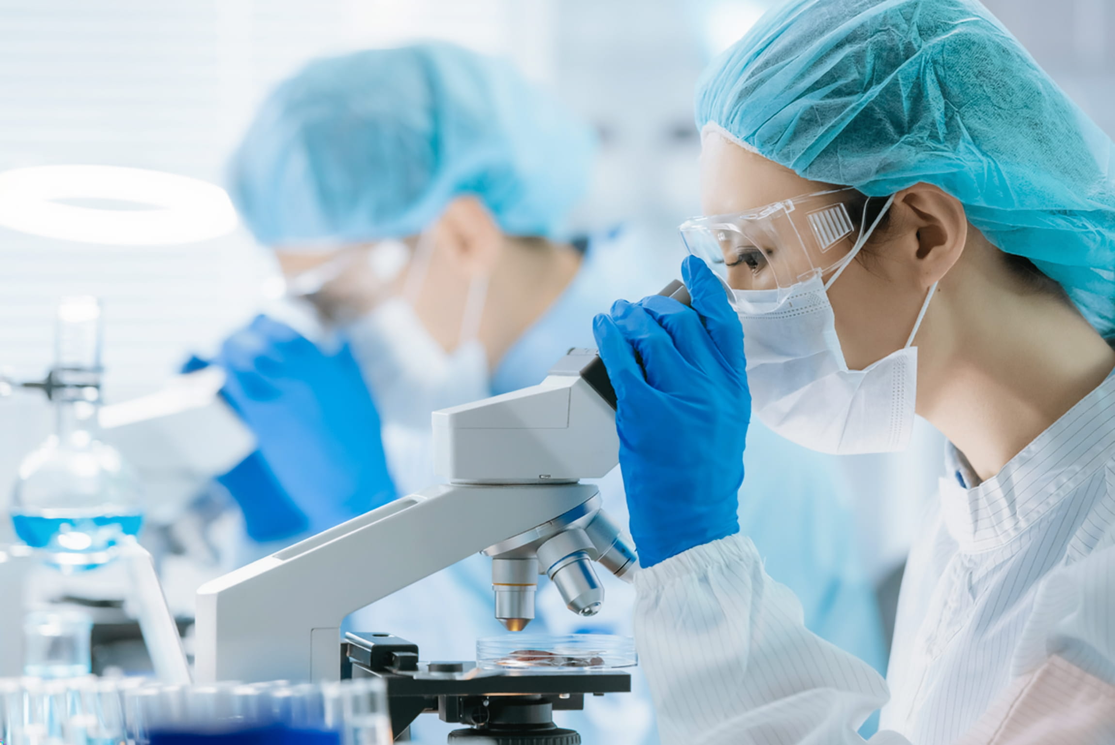 Scientists examine samples under a microscope in a laboratory setting during daytime