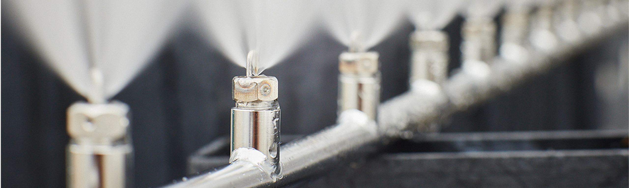 a series of MeeFog Impaction Pin Nozzle units mounted on a high-pressure manifold, producing ultra-fine water droplets.