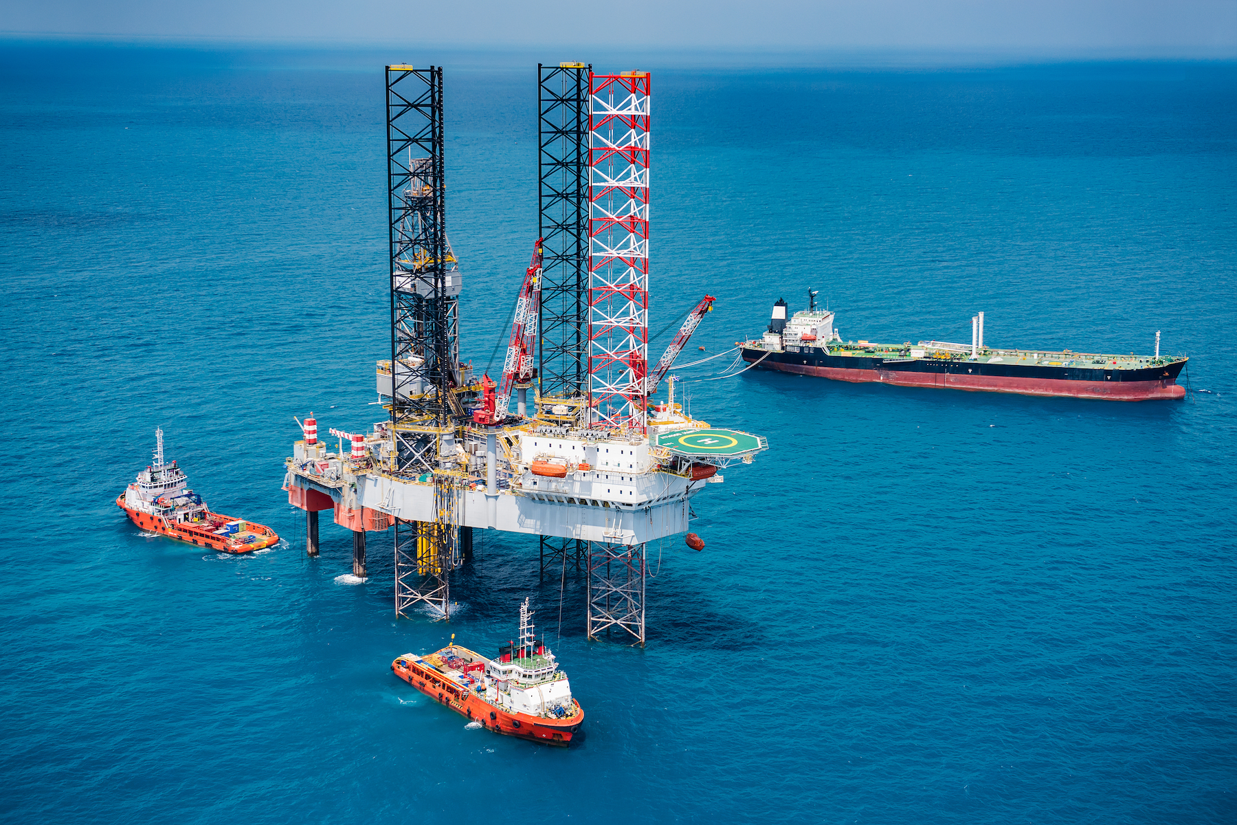 A mobile offshore drilling unit featuring a triangular or rectangular hull raised above the water on large open-truss legs
